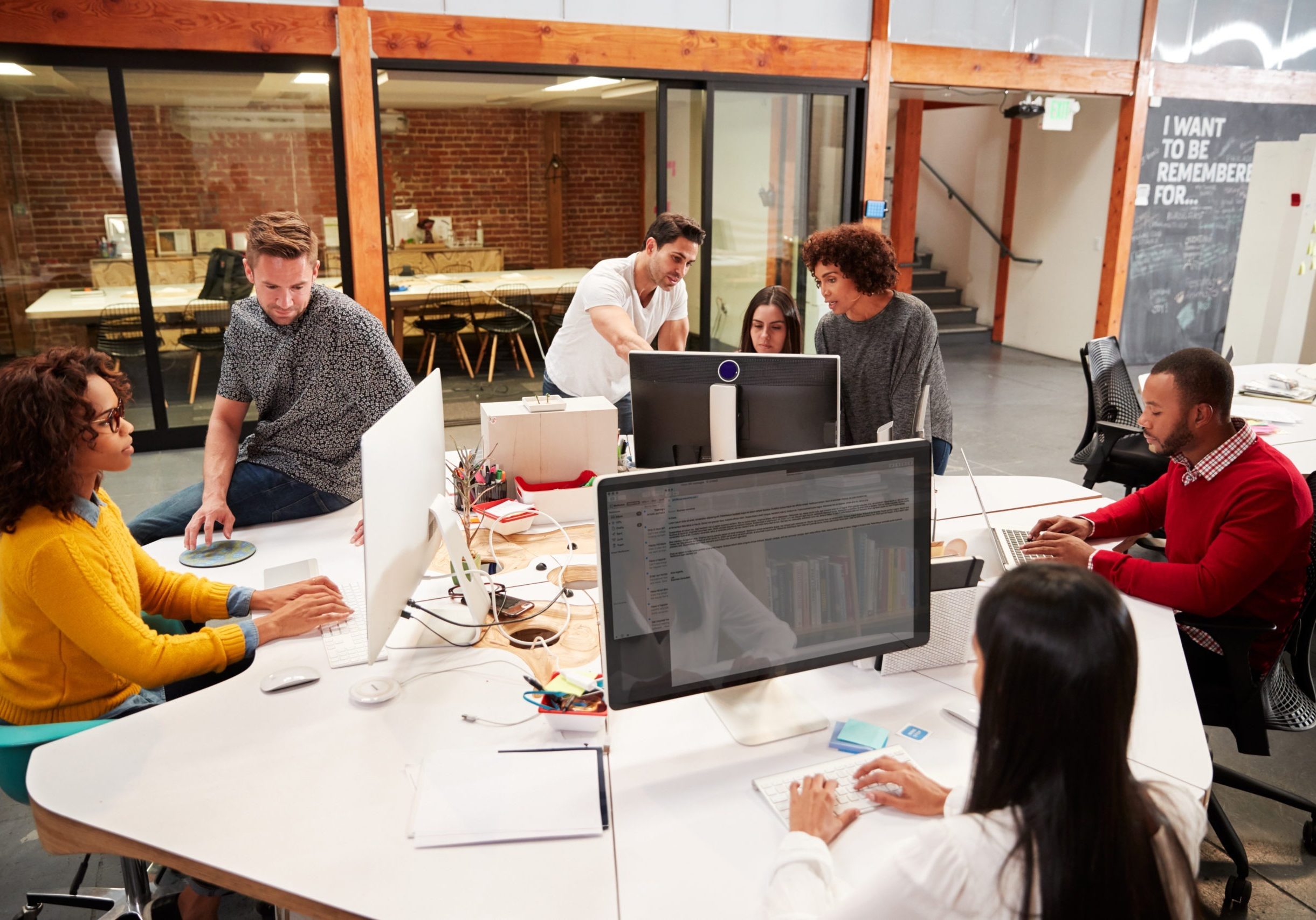 Casually Dressed Business Team Working At Desks In Modern Open Plan Office