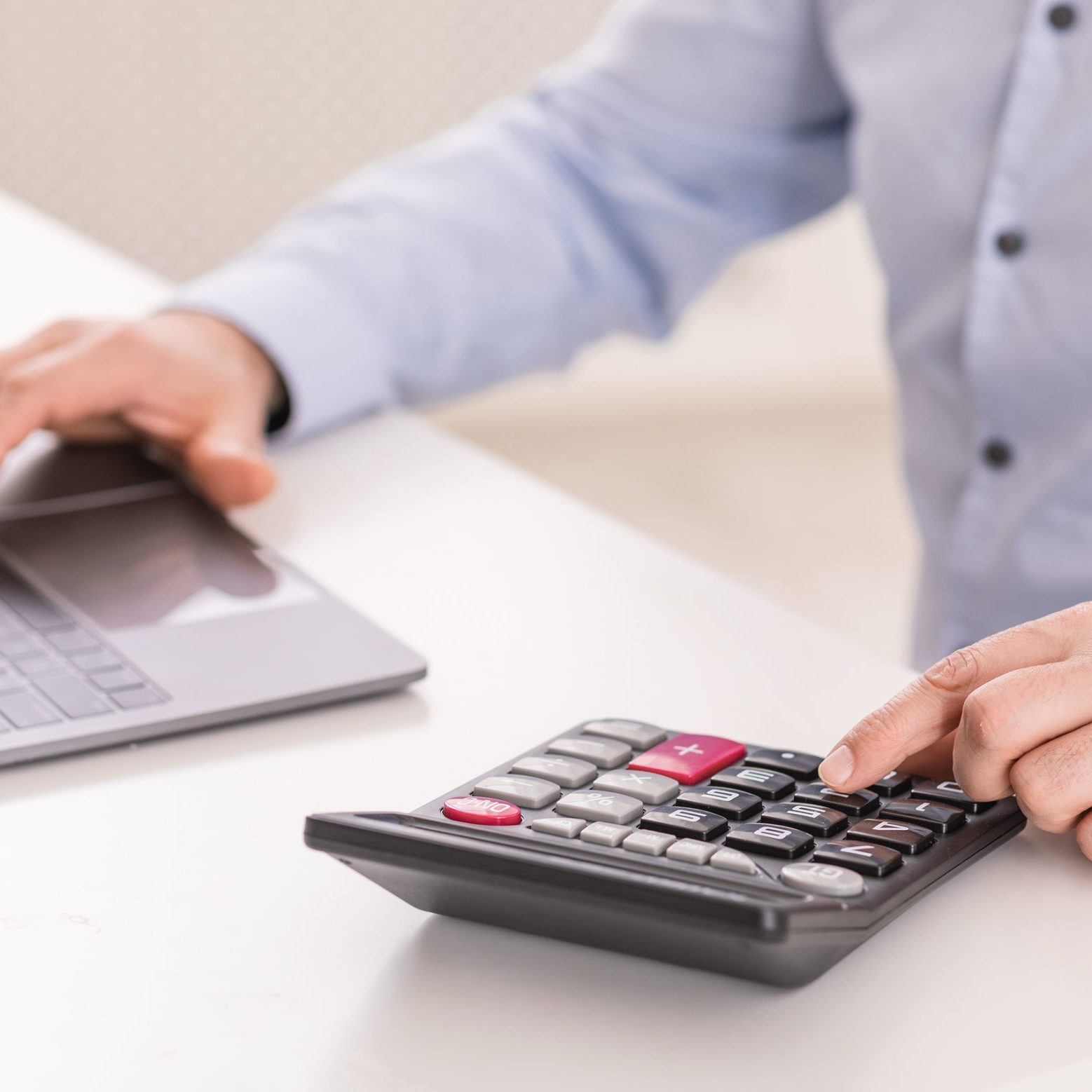 Payroll Concept. Close up of middle-aged accountant using calculator and computer, selective focus